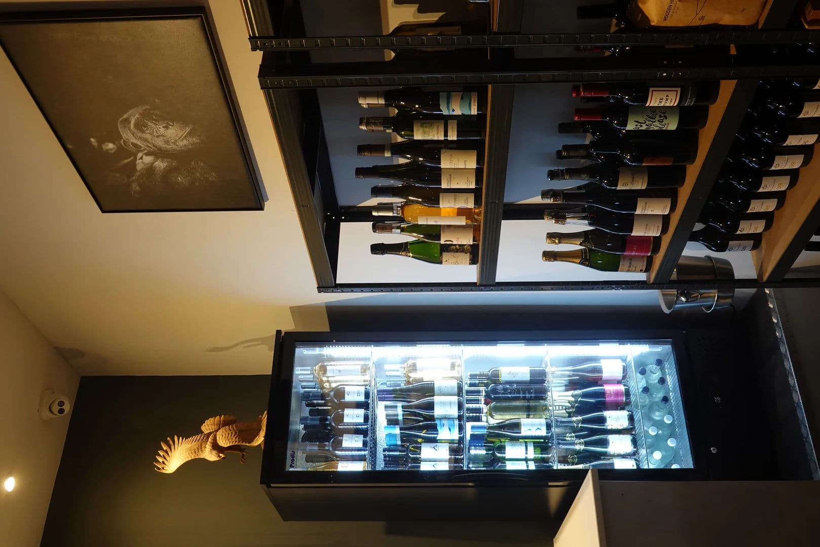 Wine display with bottles on shelves and a lit fridge