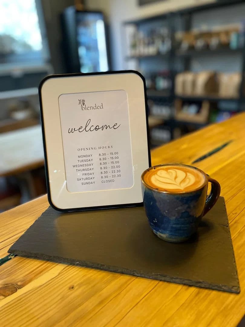 Coffee with latte art alongside the Blended welcome sign
