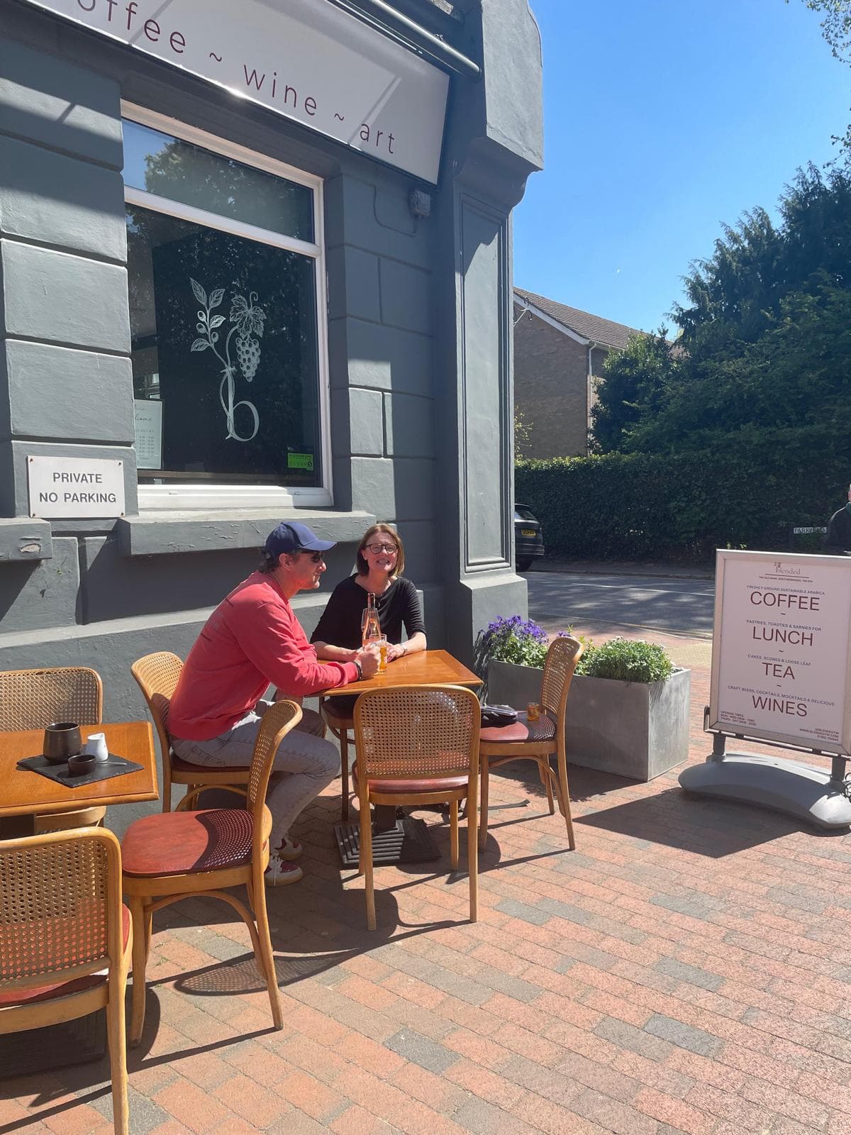 A couple chatting over drinks at an outdoor table outside Blended